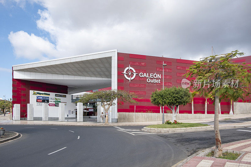 购物中心的主要入口具有现代建筑，明亮的红色立面和一个大的标志，Galeon Outlet